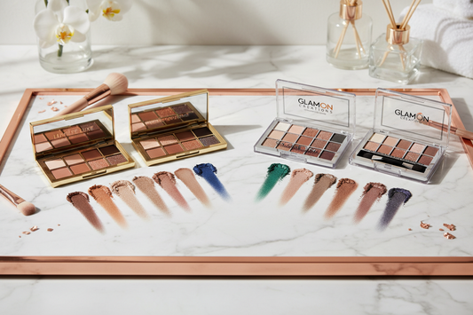 Luxury and affordable eyeshadow palettes side by side with color swatches showing warm neutrals, cool taupes, and jewel tones on white marble surface